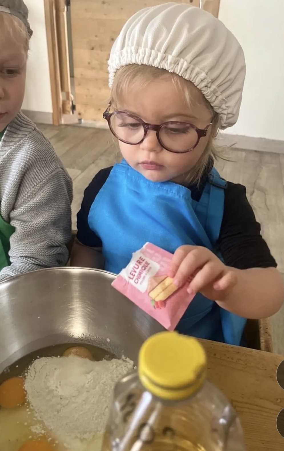 Anna en toque et tablier, préparant un gâteau.
